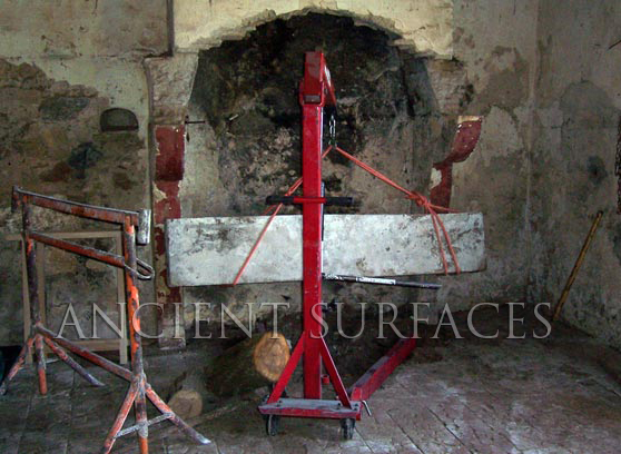A French Antique fireplace mantel getting reclaimed with the help of a hydraulic crane