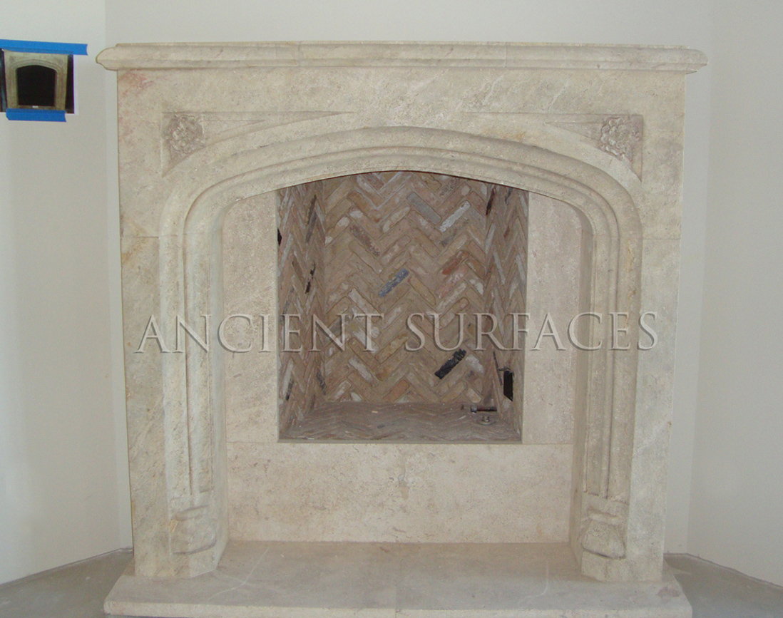 A simple Tudor fireplace hand carved in natural stone installed with herringbone bricks lining the insides of this gas burning firebox.